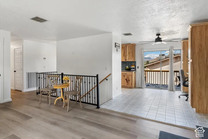 Wood-finish flooring, white walls, black metal railing, tiled floor, and a sliding glass door