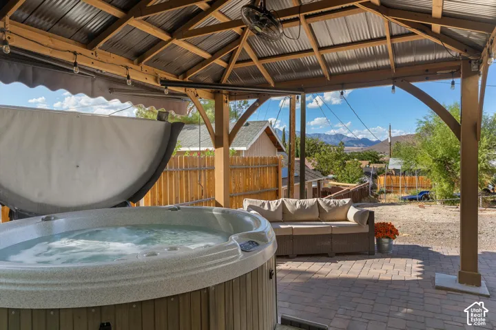 Covered patio featuring a hot tub, string lighting, and mountain scenery