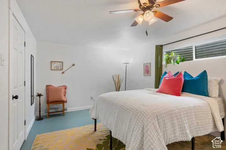 White paneled door, ceiling fan with light fixture, high-set window, and blue-toned flooring