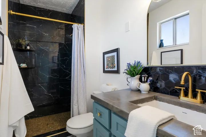 Shower featuring black marble-style tile walls, a gold-tone shower rod, and built-in shelving