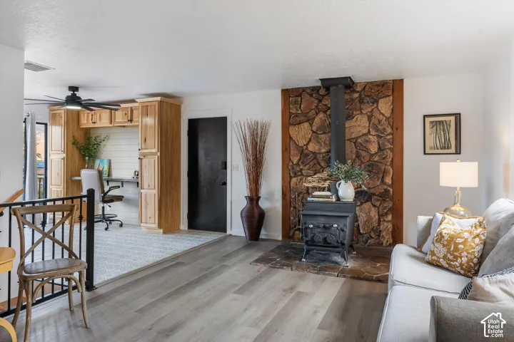 Wood-finish flooring, stone accent wall, built-in wood cabinetry, black door, and a ceiling fan