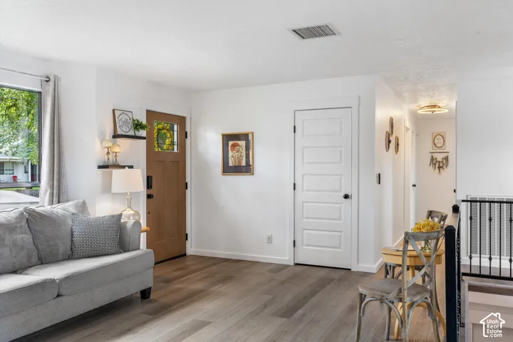 Wood-finish flooring, white walls, and bright window with white trim