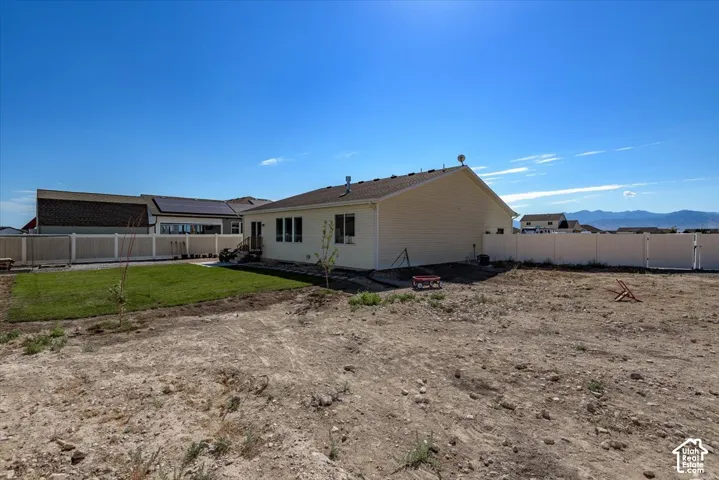 Expansive backyard with a manicured lawn, a gravel patio area, and a white vinyl privacy fence