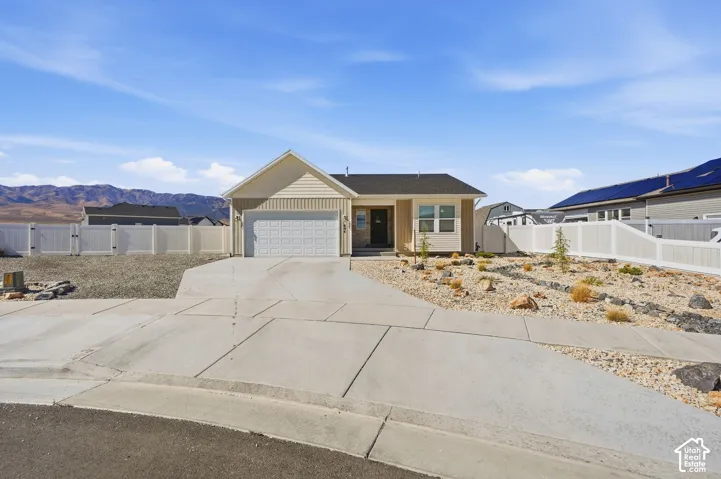 Concrete driveway, attached garage, composite shingle roof, neutral exterior siding, and a white perimeter fence