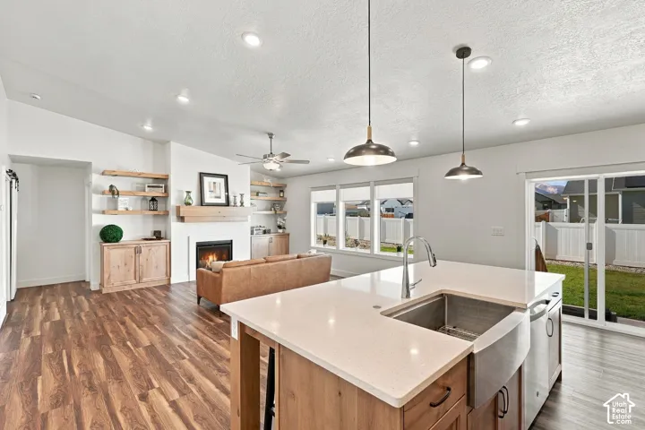Open-concept living space featuring wood-finish flooring, a white fireplace with a wood mantle, and built-in shelving