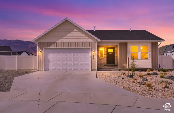 Single-story residence featuring a two-car garage, stone and siding exterior, and a gravel and rock landscaping design