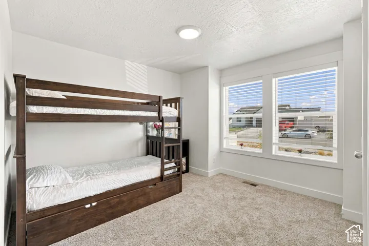 Recessed ceiling light, two large windows, white window blinds, light tone carpet flooring, white painted walls