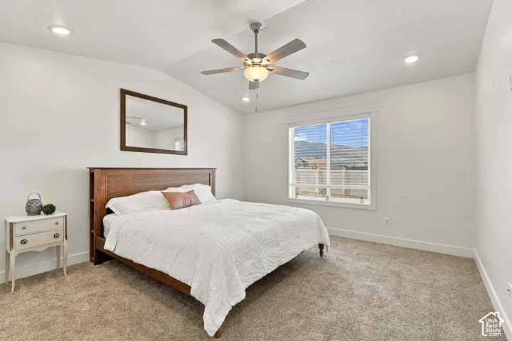 Vaulted ceiling with a ceiling fan, recessed lighting, wall-to-wall carpeting, and a large window with horizontal blinds