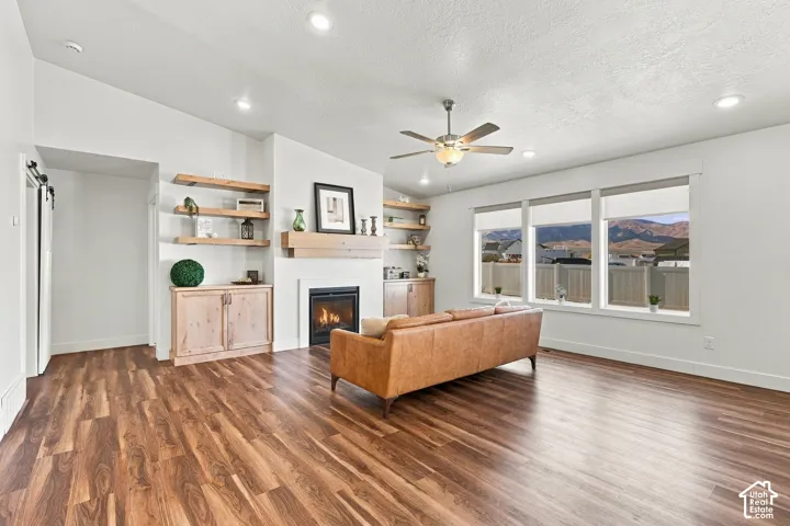 Wood-finish flooring, recessed lighting, and built-in shelving complement the fireplace with a wood mantle