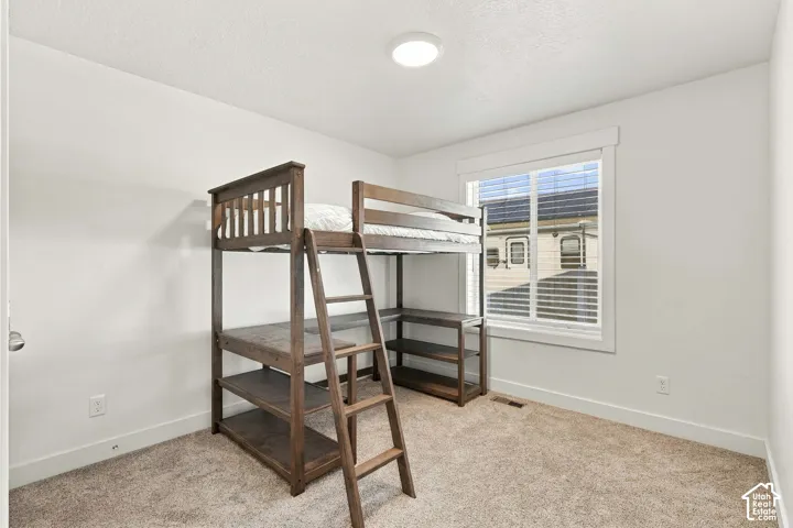 Neutral wall paint, carpet flooring, a single window with blinds, and a flush mount ceiling light fixture