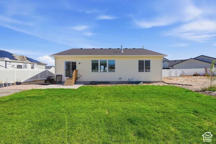 Expansive green lawn with a concrete patio and wood steps leading to a sliding glass door
