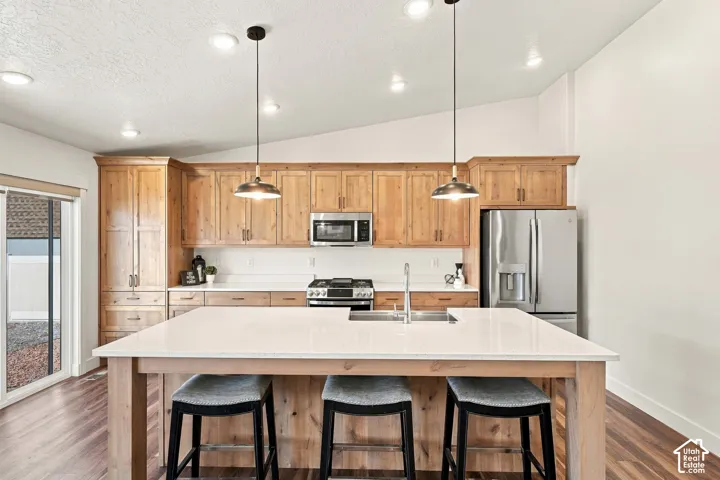 Kitchen featuring wood-finish cabinetry, stainless steel appliances, a center island with countertop seating, and recessed lighting