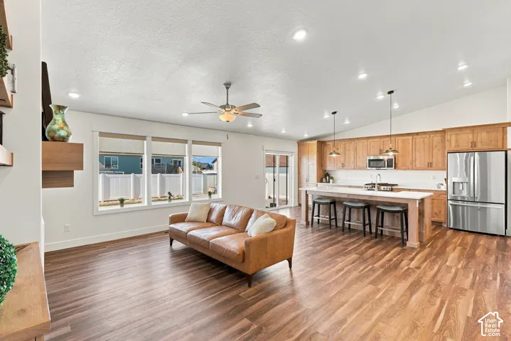 Open-concept living space featuring wood-finish flooring, recessed lighting, and vaulted ceilings