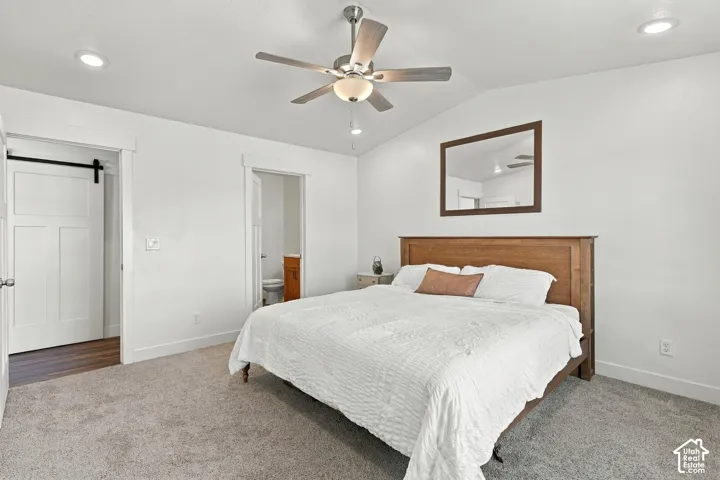 Master bedroom featuring a wood-finish bed frame, recessed ceiling lighting, ceiling fan with integrated light fixture, carpeted flooring, and a framed mirror accent wall