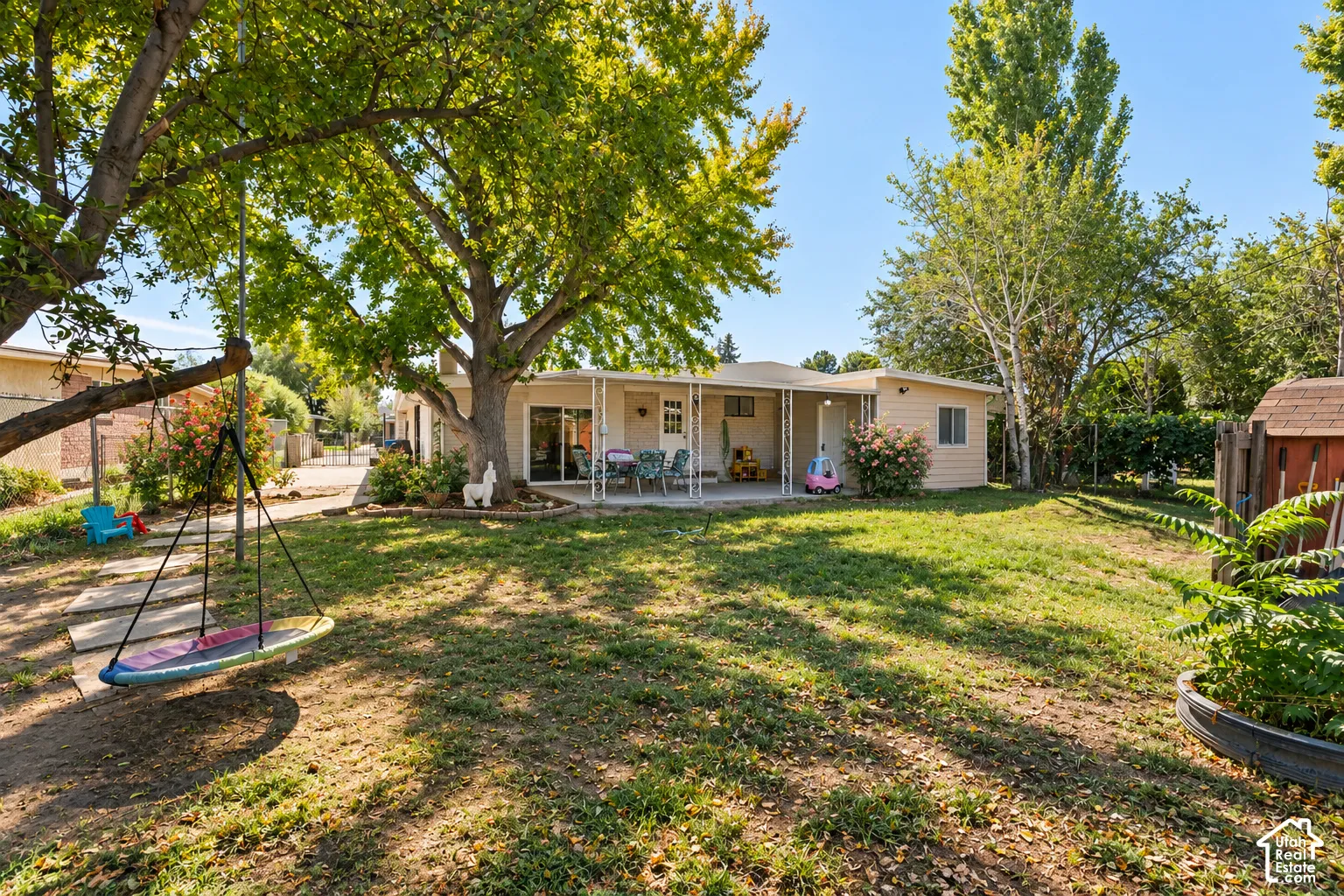 Expansive backyard featuring mature shade trees, a covered patio, and a separate storage shed