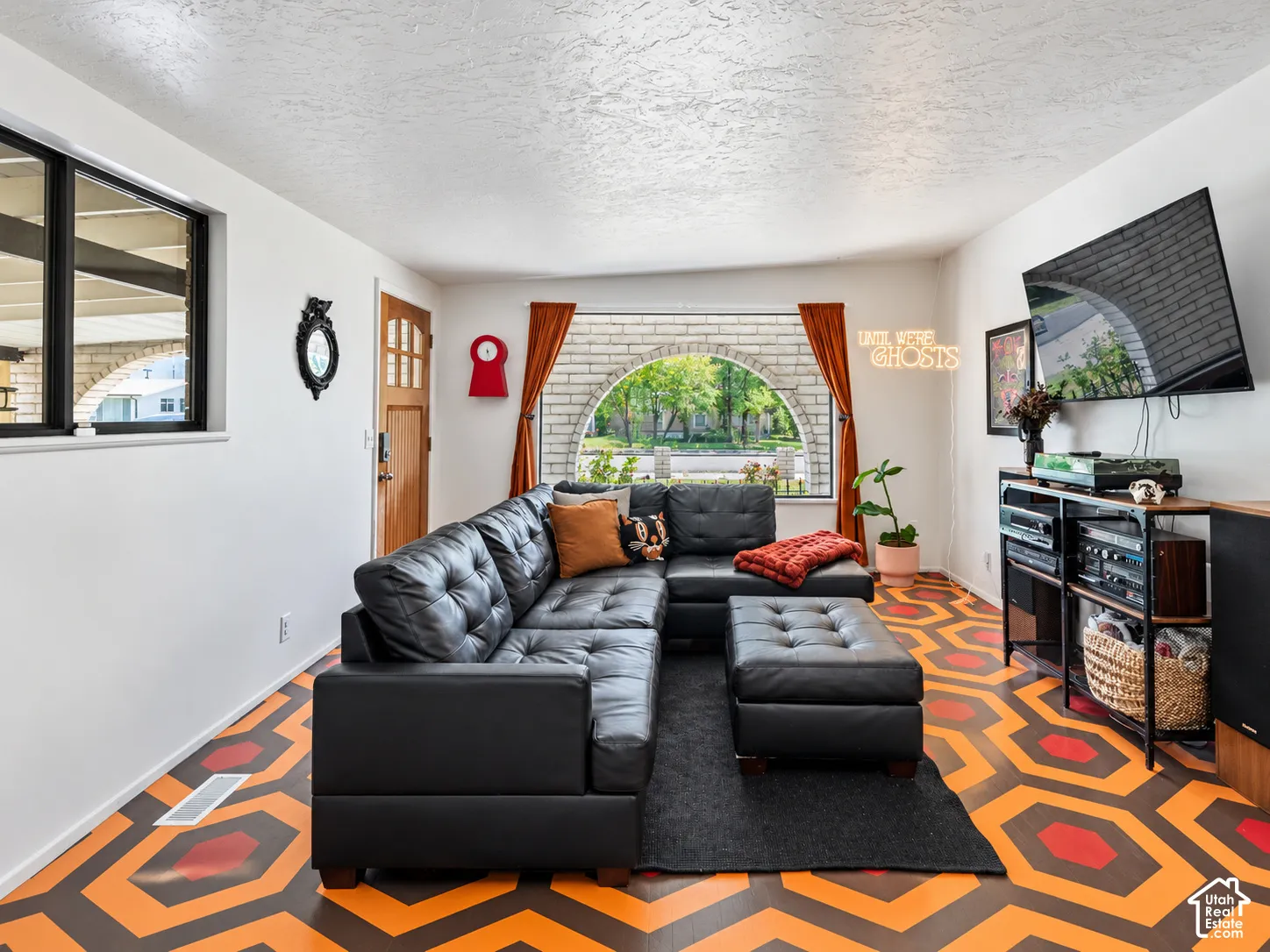 Arched window, geometric pattern flooring, wood entry door, and black-framed windows