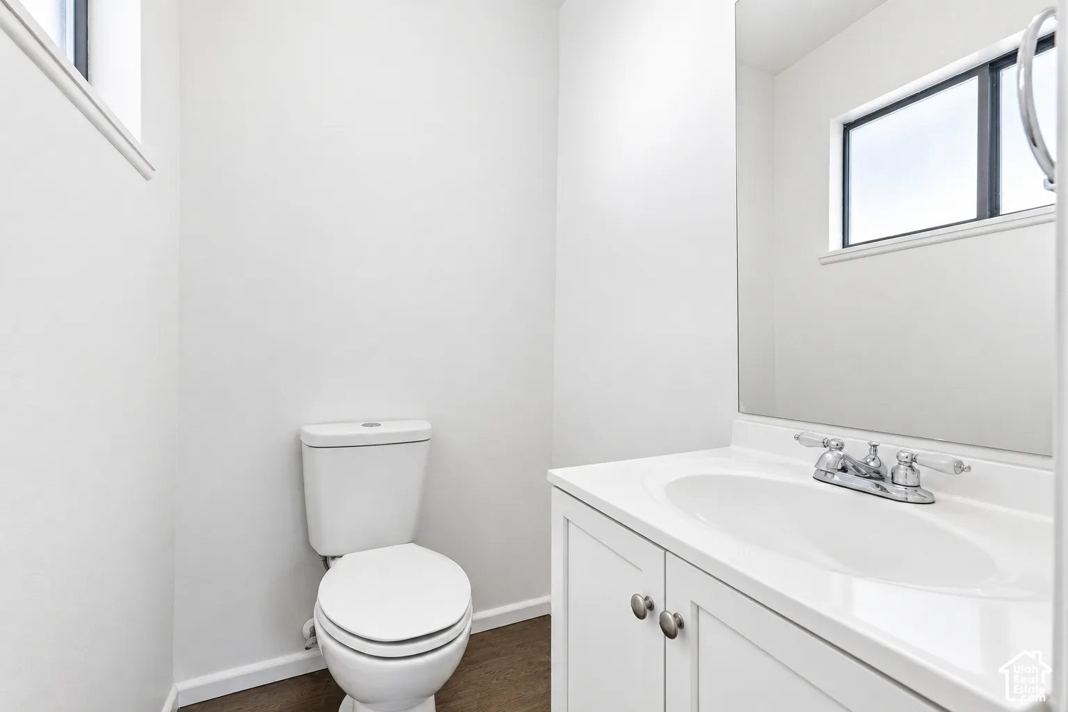 White vanity with an integrated sink and chrome faucet, set against a large wall-mounted mirror