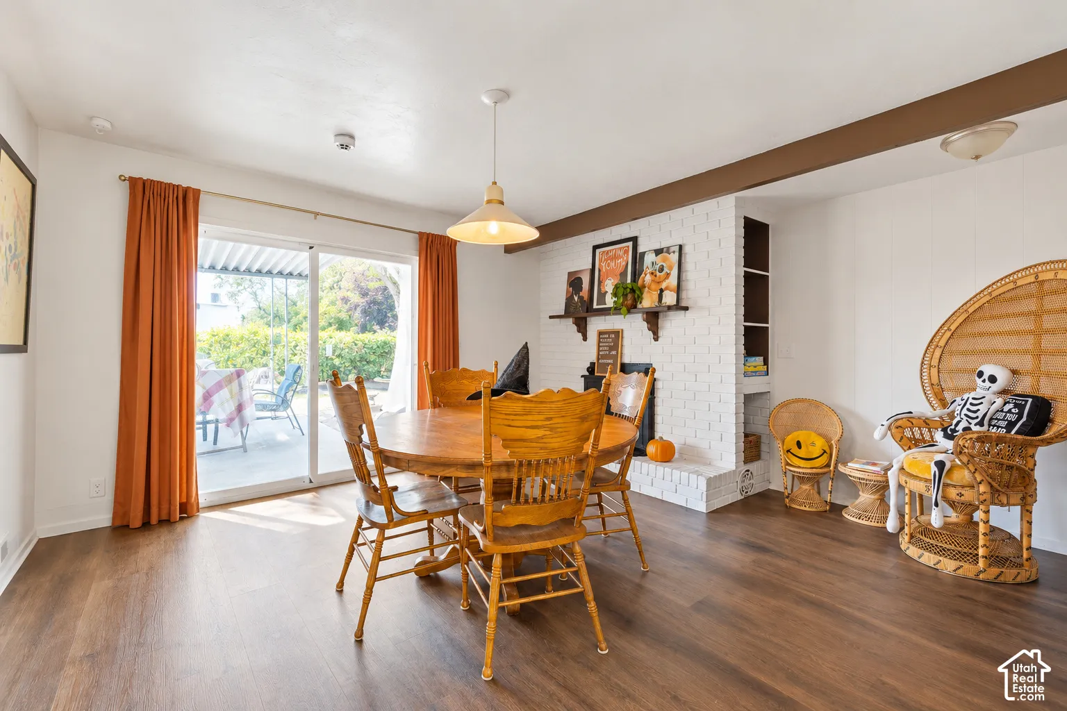 Wood-finish flooring, white painted brick fireplace, built-in shelving, glass sliding door, and pendant lighting