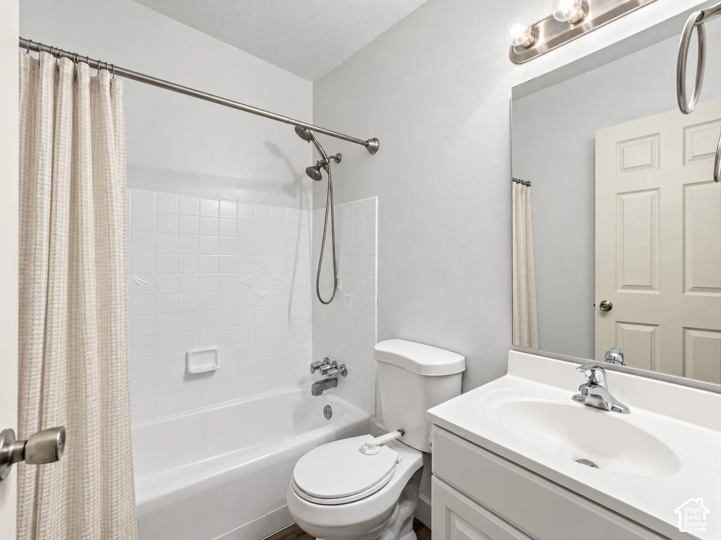 White bathroom vanity with integrated sink, chrome faucet, and overhead bar lighting