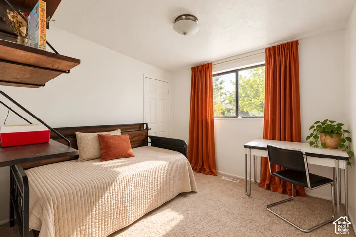 Built-in shelving, window with natural light, textured carpeting, and a flush-mount ceiling light fixture