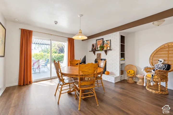 Wood-finish flooring, white painted brick fireplace, built-in shelving, glass sliding door, and pendant lighting