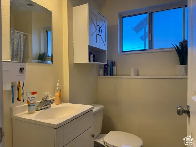 Vanity with integrated sink, wall-mounted storage cabinet, mirror, and sliding window