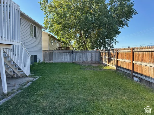 Expansive backyard featuring a manicured lawn, a full privacy fence, and mature trees