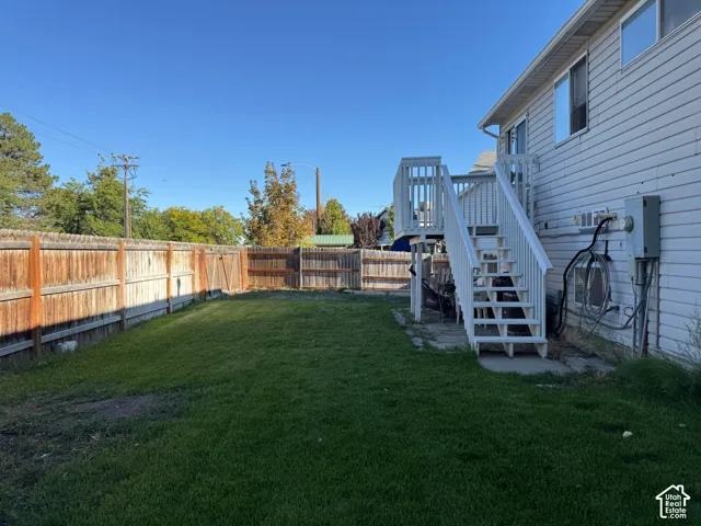 Expansive backyard featuring a manicured lawn, wood fencing, and a multi-level deck with stairs