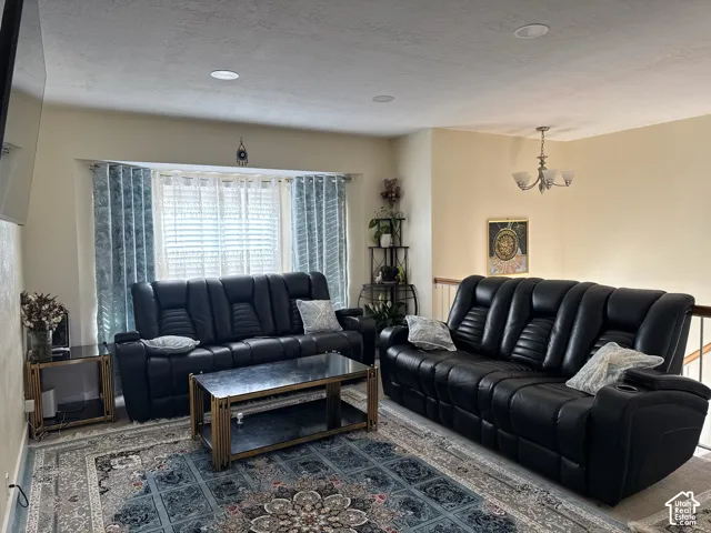 Recessed ceiling lighting, window with horizontal blinds, decorative window treatments, and a multi-arm chandelier