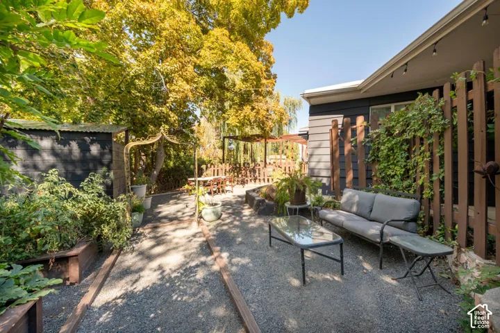 Gravel patio with a pergola, raised garden beds, and mature trees