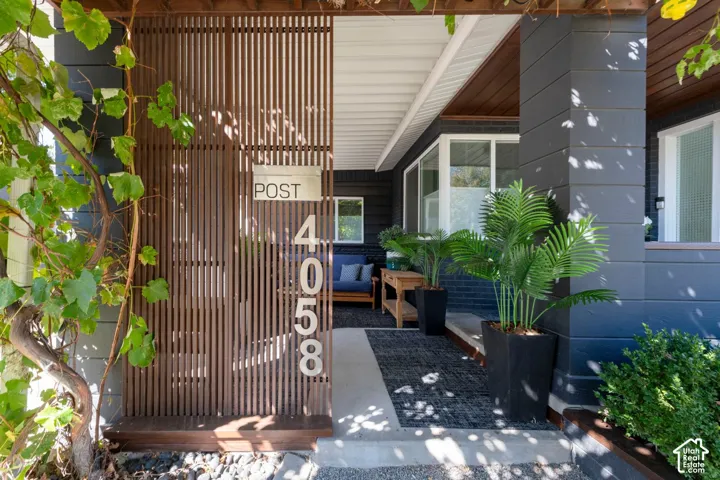 Wood slat privacy screen, dark gray exterior siding, large picture windows, covered porch, and concrete pathway