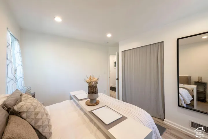 Recessed ceiling lighting, light wood-finish flooring, white wall paint, and a wall-mounted full-length mirror