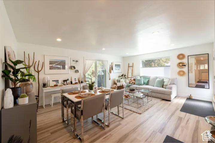 Open-concept living area with wood-finish flooring, recessed lighting, and large windows