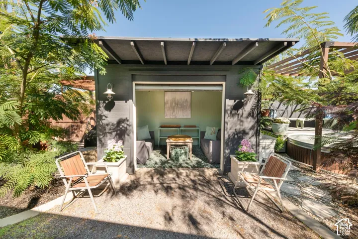 Dedicated outdoor structure featuring exterior wall sconces, a sloped roof, and a gravel ground covering