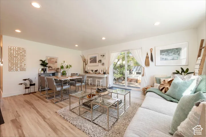 Open-concept living area with wood-finish flooring, recessed lighting, and a sliding glass door