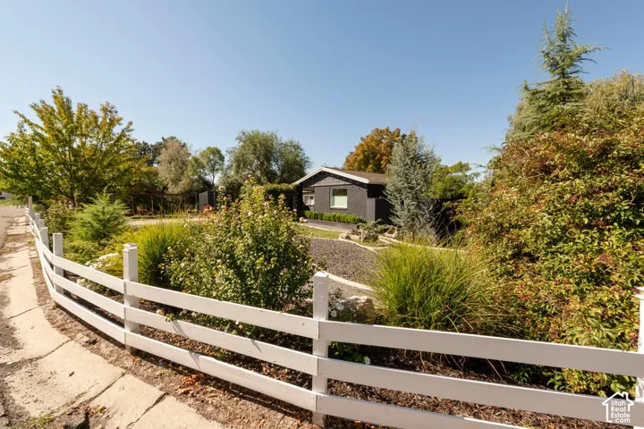 White painted fence, mature trees, and established landscaping
