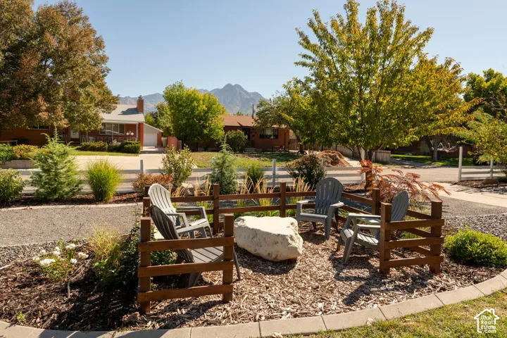 Outdoor seating area featuring a wood fence, a large decorative boulder, and ground cover