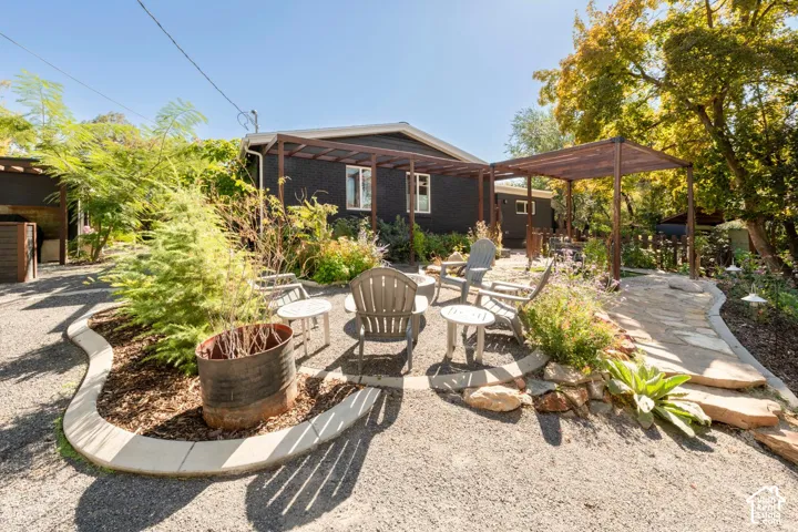 Gravel patio area with wood pergolas, stone pathway, and landscaped garden beds