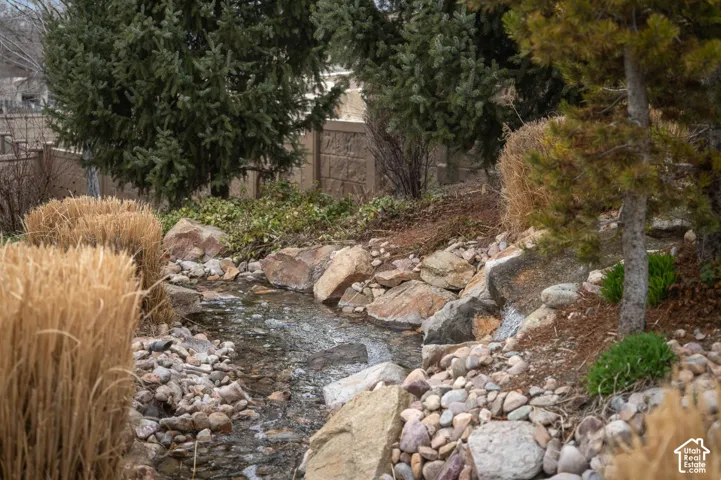 Water feature with a stone and pebble bed, surrounded by varied plant life and large boulders