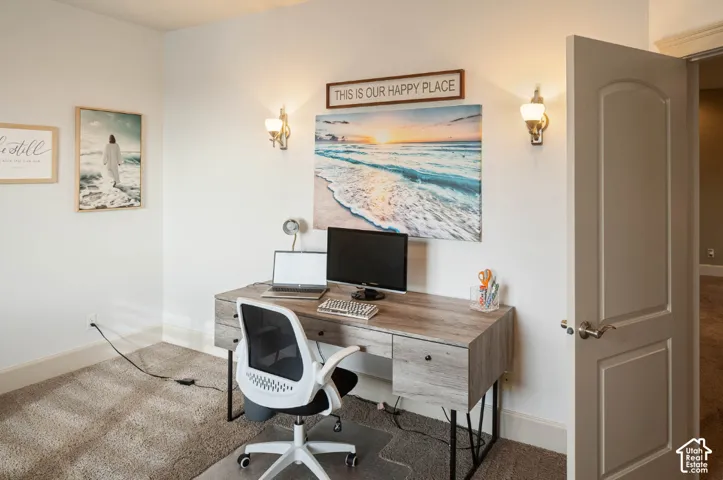 Wall-mounted sconce lighting illuminates a wood-finish desk with a built-in drawer