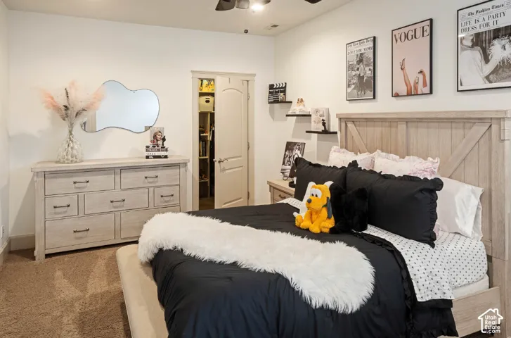 Warmly carpeted room featuring a ceiling fan, a built-in closet with an arched door, and a light-toned wood-finish headboard