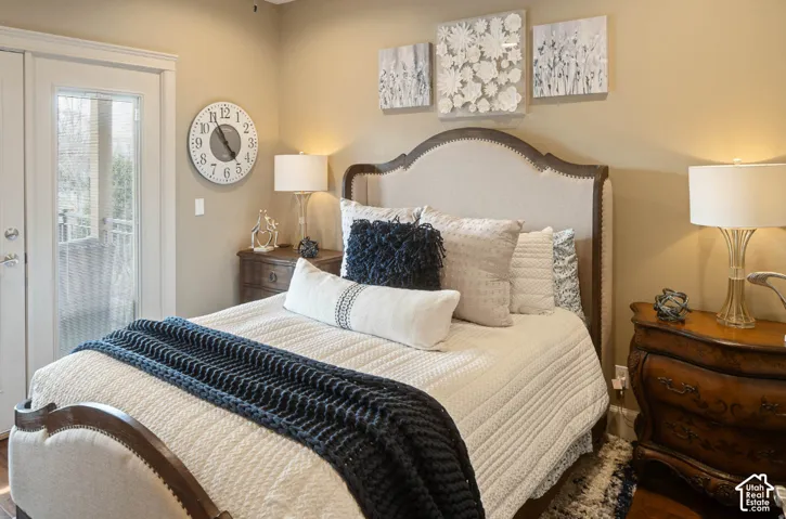 Bedroom with arched upholstered headboard featuring nailhead trim, crisp white bedding with textured quilting, and layered throw pillows in neutral tones