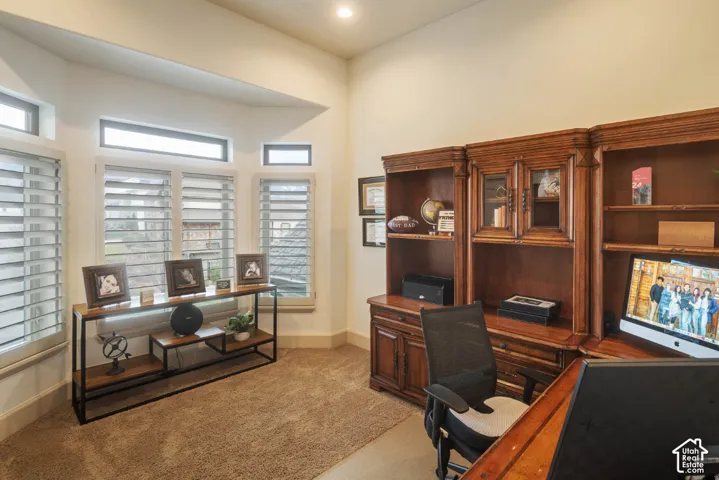 Built-in wood cabinetry with glass-front display, multiple windows with plantation shutters, and recessed lighting