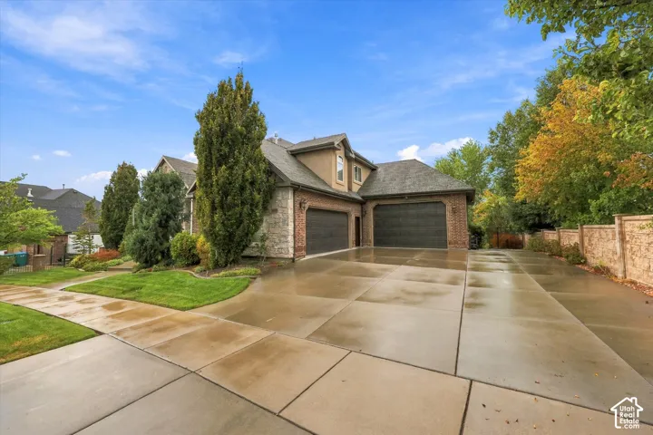 Stucco and brick exterior with stone accents, featuring a multi-car driveway and a two-car garage