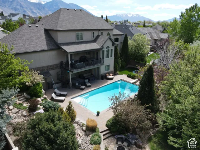 Multi-level property featuring a large patio, a built-in swimming pool, and a balcony with an exterior spiral staircase