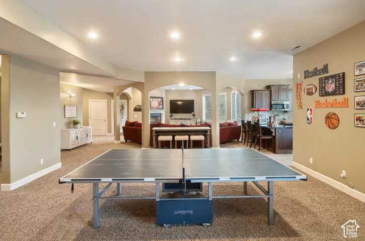 Carpeted entertainment area featuring recessed lighting, arched doorways, and a built-in wet bar with cabinetry