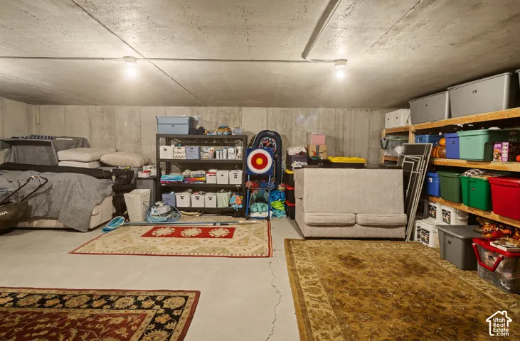 Concrete flooring, exposed concrete walls, track lighting, and built-in shelving