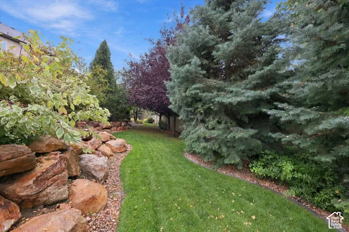 Manicured lawn bordered by a stone rockery and mature trees