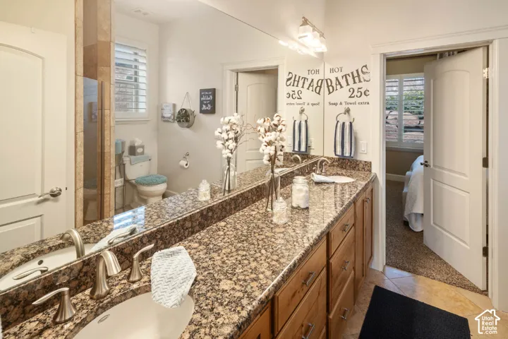 Dual vanity with undermount sinks, granite countertop, wood-finish cabinetry, and brushed nickel fixtures