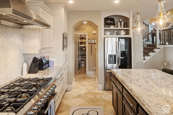 Gourmet kitchen with stainless steel appliances, granite countertops, and a full-height tile backsplash